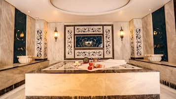 Bathroom features a central sink, elegant wall sconces, and a decorative mirror.