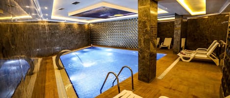 A spa pool area with a ceiling mural, wooden flooring, and lounge chairs.