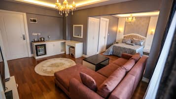 Un dormitorio moderno con una cama grande, una zona de estar con sofá y una kitchenette.