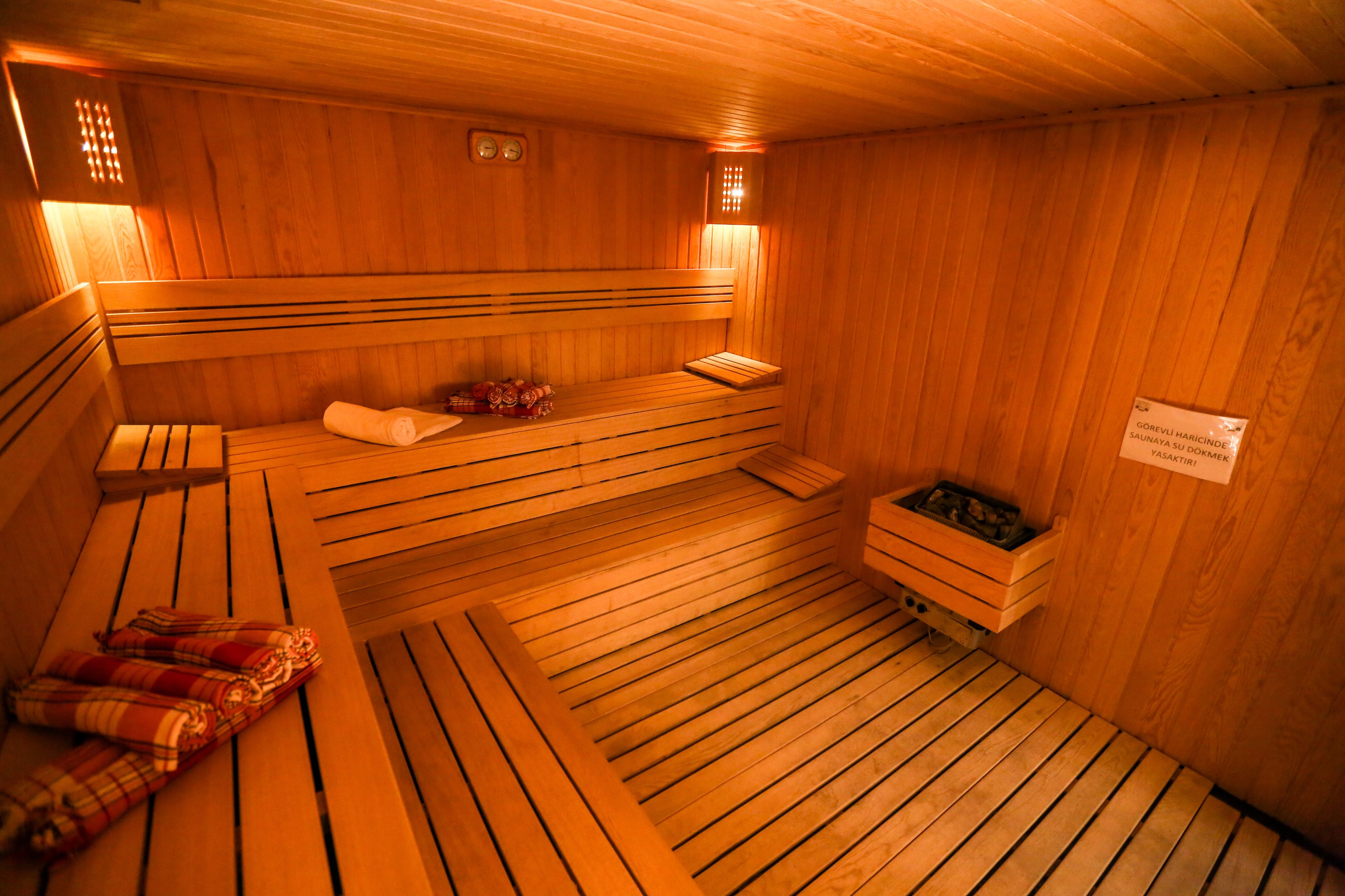 Eine Holzsauna mit Bänken, eine Bank mit einem Handtuch und eine kleine Holzablage.