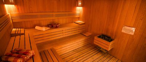Eine Holzsauna mit Bänken, eine Bank mit einem Handtuch und eine kleine Holzablage.