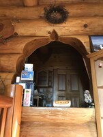 Interior de madera con un amplio arco de entrada, un banco de madera, un cartel y un cuadro en la pared.