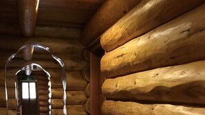 A log cabin interior with a wooden floor, a central archway, and a door leading to another room. - Mori no Log Hotel Kamloops (Shinano)