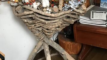 A rustic wooden basket with branches and cotton bolls, placed on a tripod stand.