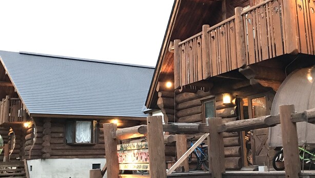 A rustic log cabin with a balcony and a concrete water tank. - Mori no Log Hotel Kamloops (Shinano)