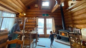 A rustic wooden cabin interior with a dining area, a fireplace, and a window. - Mori no Log Hotel Kamloops (Shinano)