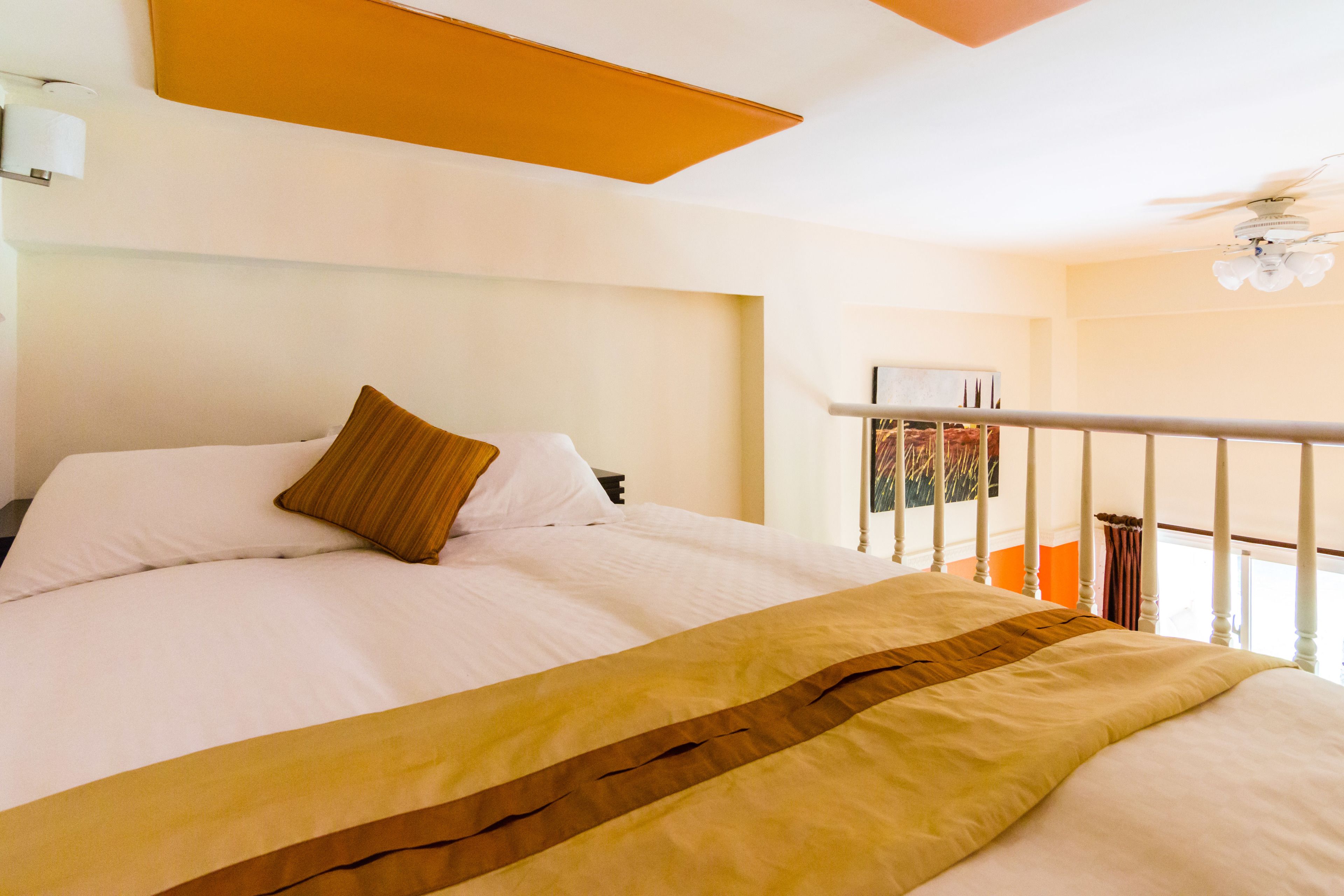 Habitación de hotel con una cama grande, ventilador de techo y vistas al exterior.