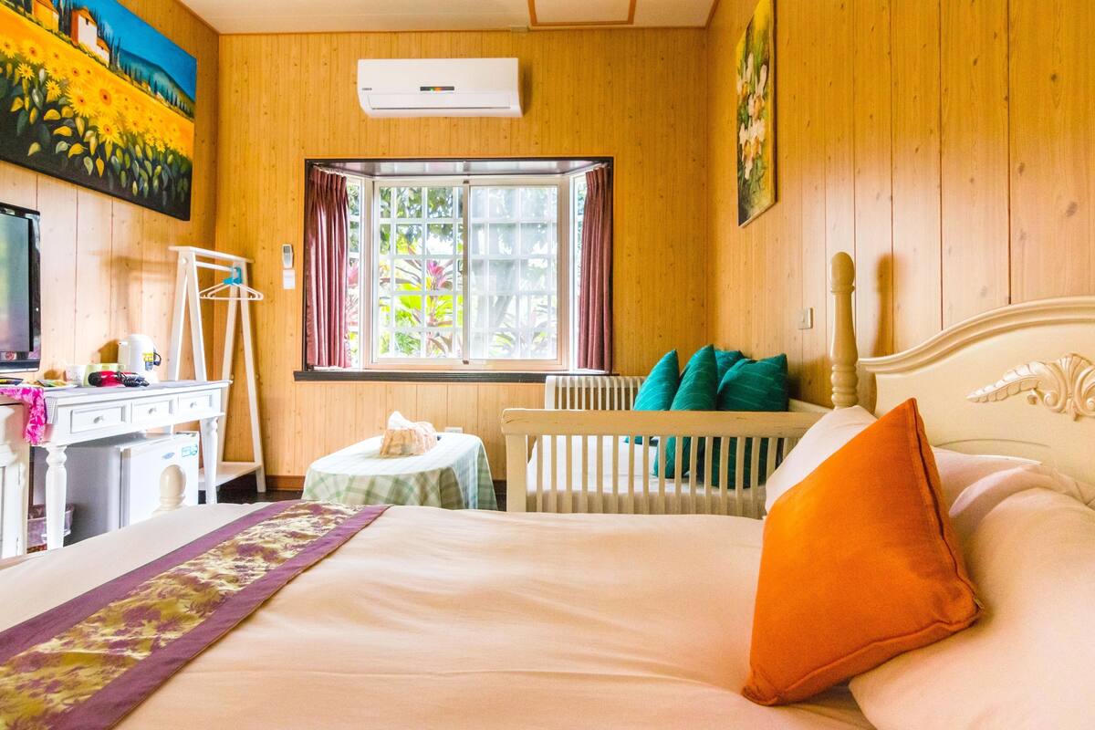 A room with a bed, a desk, a chair, a radiator, and a window with curtains.