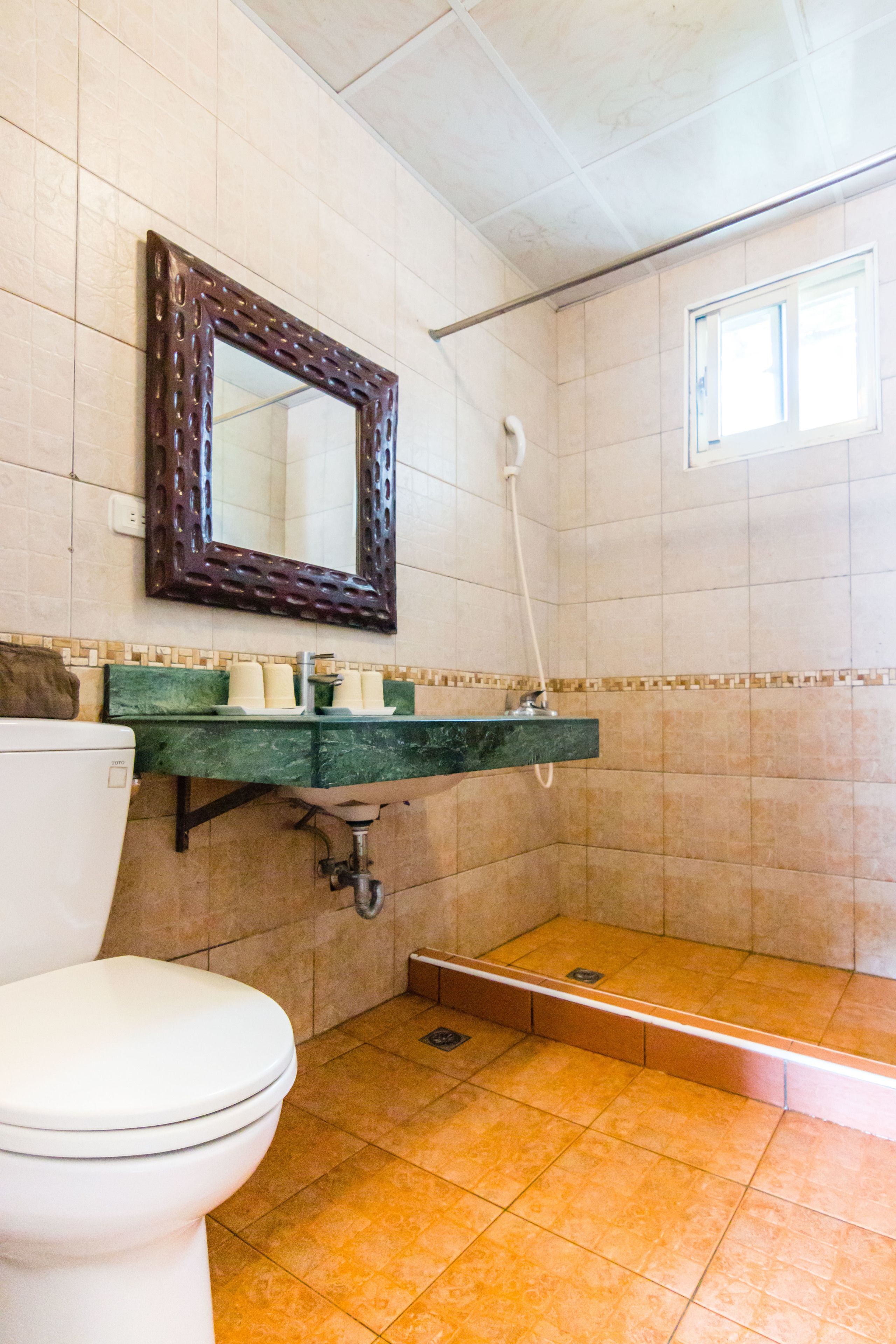 A bathroom with a toilet, a sink with a mirror, and a shower area.
