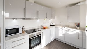 A modern kitchen with white cabinets, stainless steel appliances, and a wooden countertop. - Abodebed - Oval View (Hemel Hempstead)