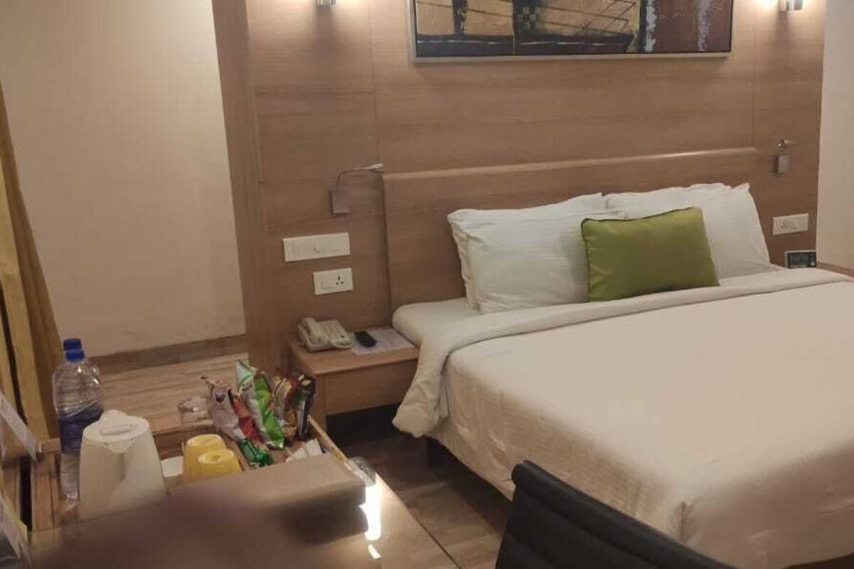 A hotel room with a bed, bedside table, and a wall-mounted phone.