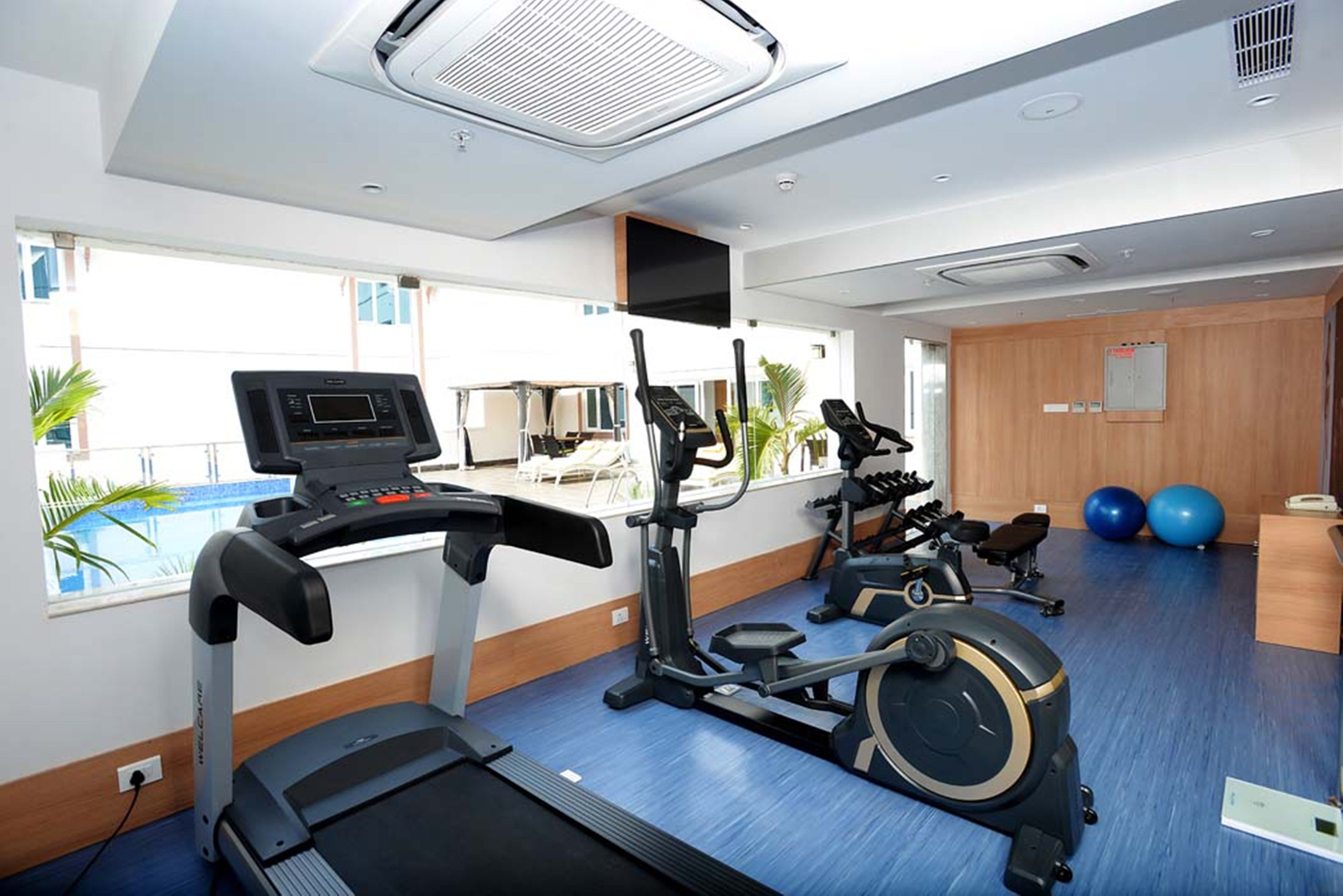 A gym with treadmills, elliptical machines, and exercise balls.