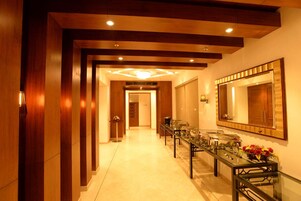 Un pasillo de hotel con paneles de madera, una larga mesa de recepción y un espejo grande en la pared.