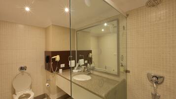 A modern bathroom with a glass-enclosed shower, a toilet, and a sink with a mirror above it.