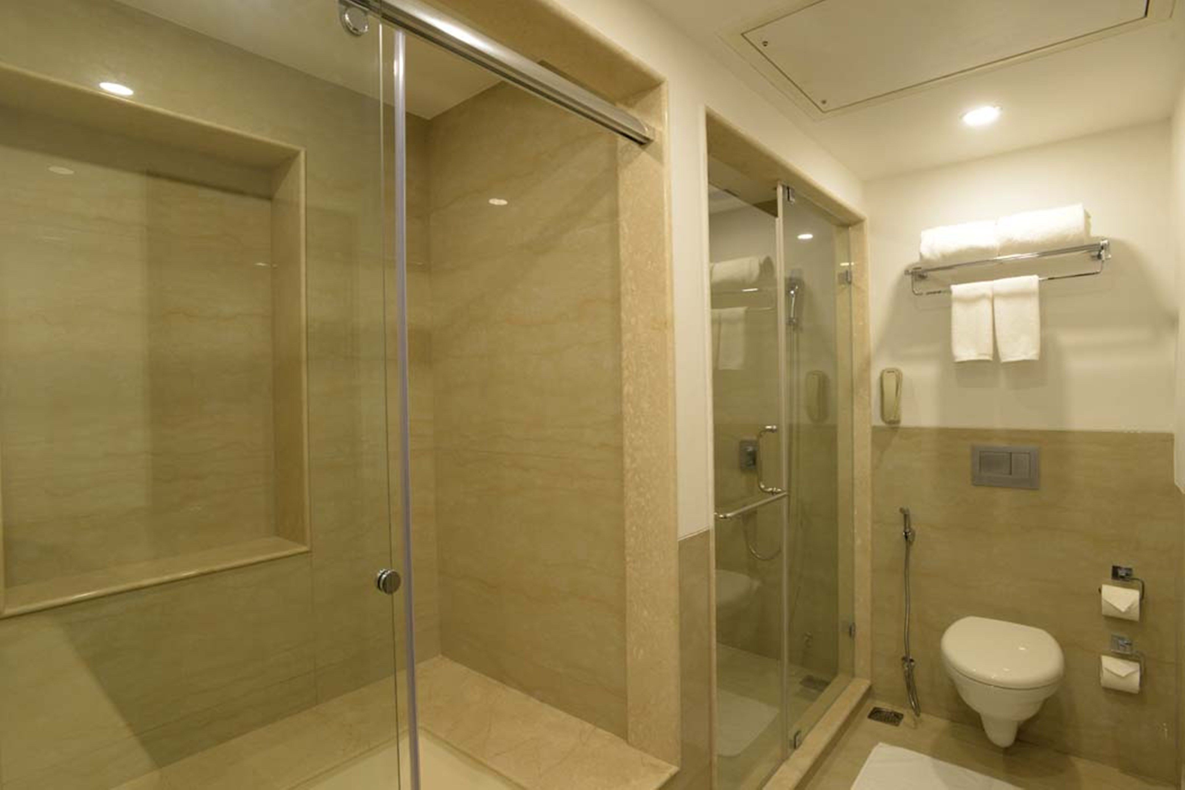 Une salle de bain moderne dotée d’une douche à parois de verre, de toilettes et d’un lavabo.