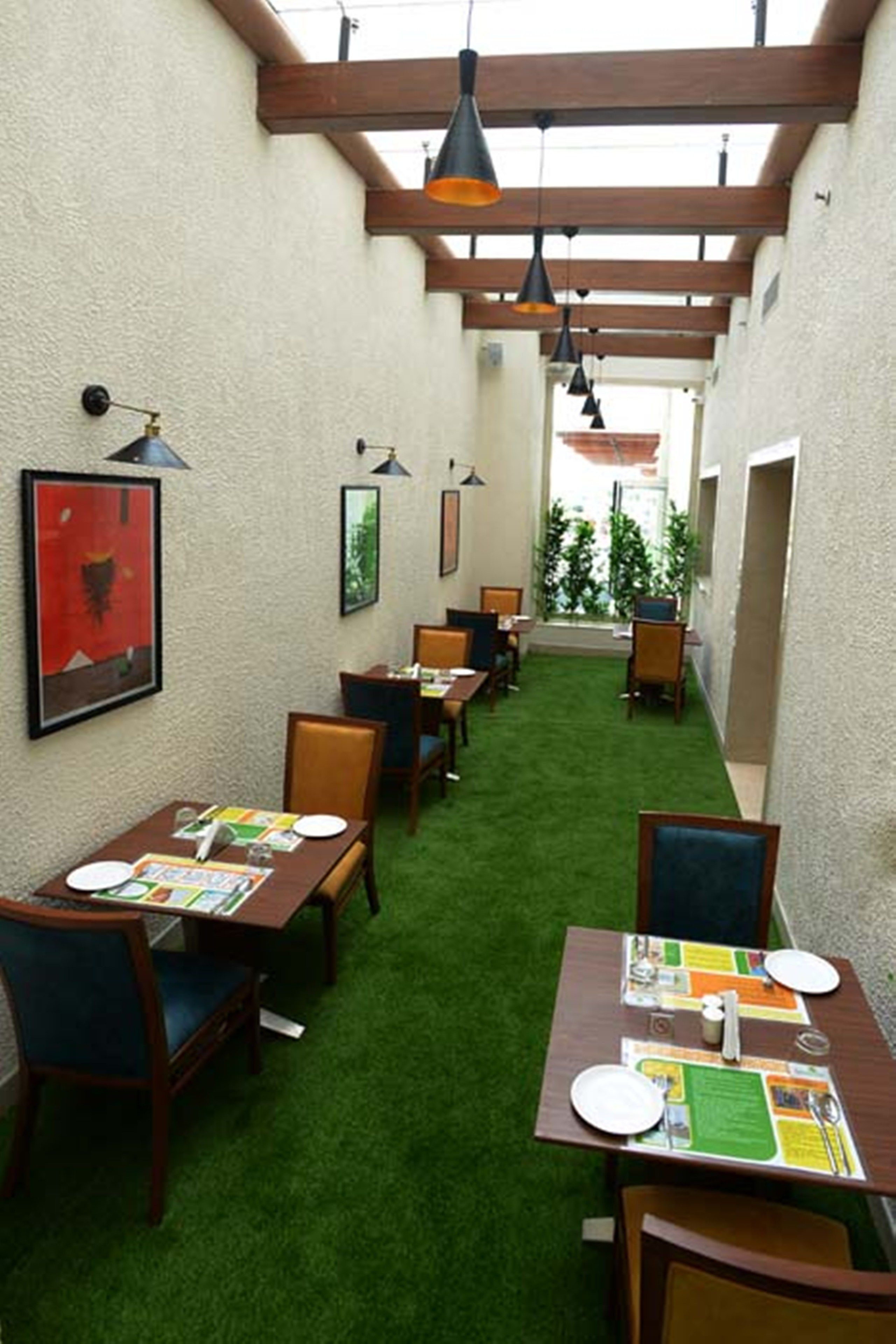 A restaurant with tables and chairs, a green carpet, and hanging lights.
