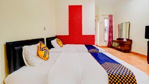 Habitación de hotel con dos camas, una pared de acento roja, un aparador de madera y un televisor.