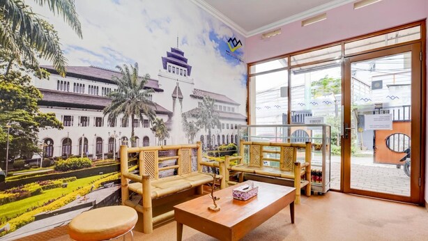 Una habitación con un mural de un edificio histórico, dos sofás de madera, una mesa de centro y vista a la calle a través de un ventanal.