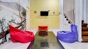 Una habitación con un mural de paisaje nevado, un televisor de pantalla plana montado en la pared, una pequeña mesa naranja y una escalera de madera.