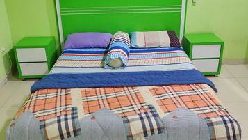 A bed with a green headboard, two bedside tables, and a telephone on the wall.
