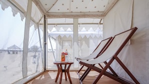 Ein mit Zeltdach versehenes Zimmer mit einer Hängematte, einem kleinen Tisch mit einer Flasche und Blick auf den Strand.