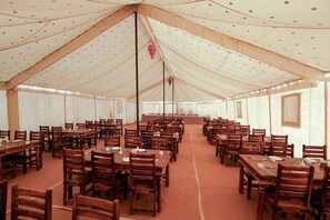 A large tent with multiple dining tables and chairs, arranged in rows. - Desert Adventure Camp Jaisalmer (Jaisalmer)