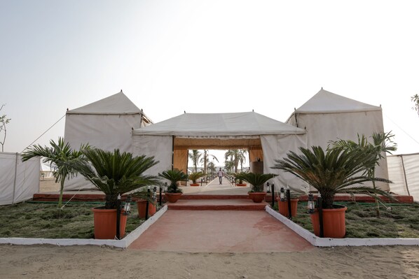 A desert resort entrance with three large tents, a central walkway, and potted palm trees. - Desert Adventure Camp Jaisalmer (Jaisalmer)