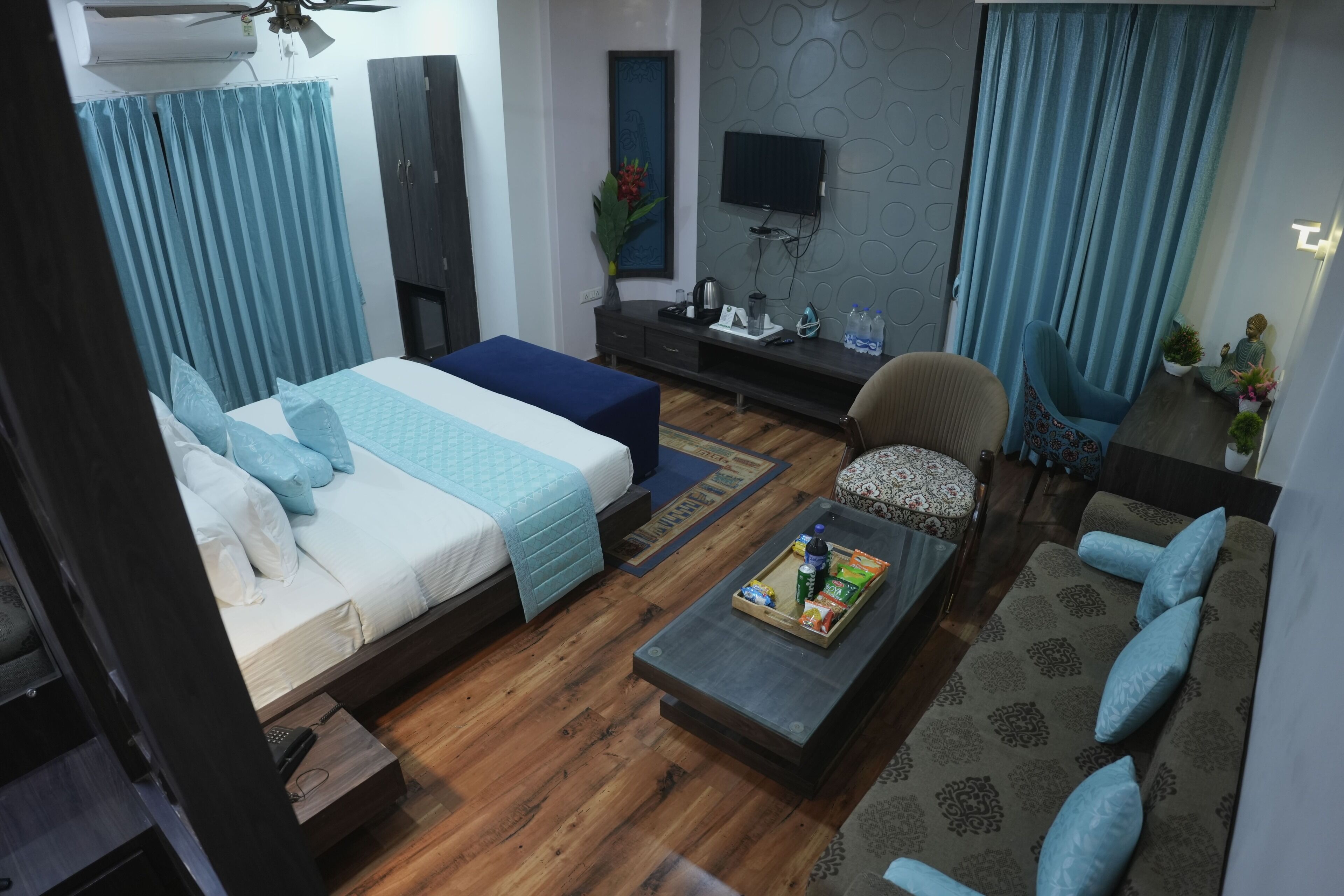 Quarto de hotel moderno com cama, sofá e uma pequena televisão.