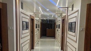 A hallway with a glossy tiled floor, framed artwork on the walls, and recessed lighting. - Ashoka Residency Hotel (Bhilwara)