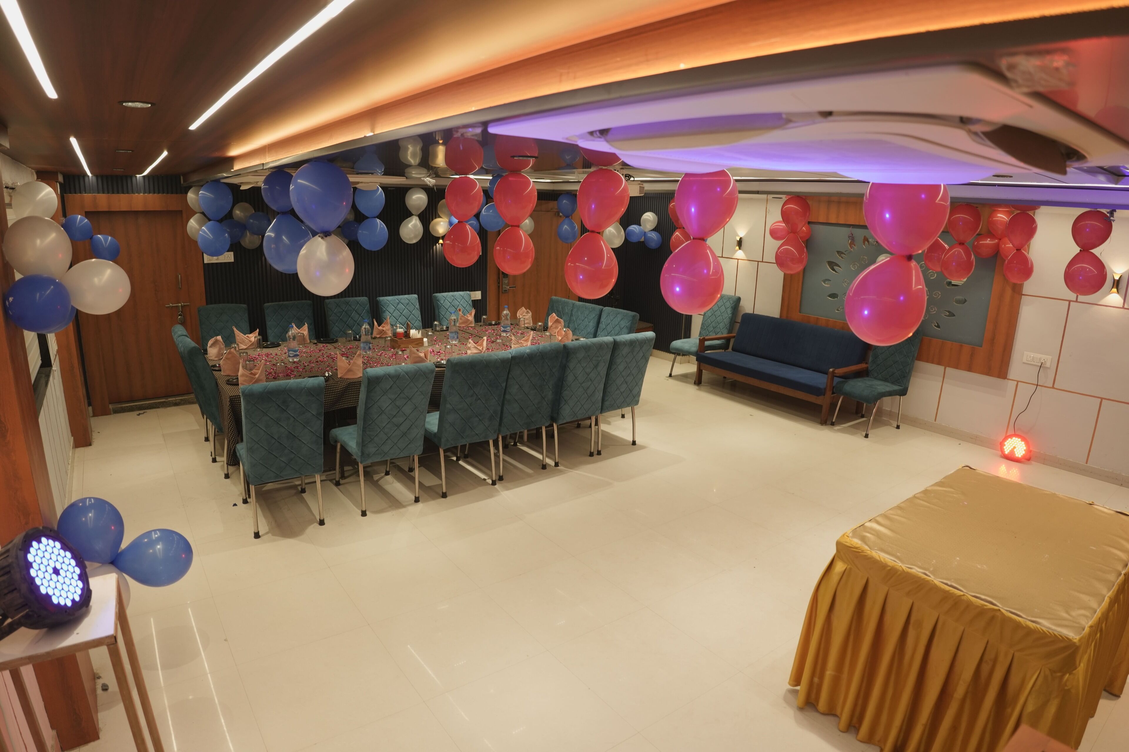 A banquet hall with a long table set for a meal, surrounded by teal chairs.