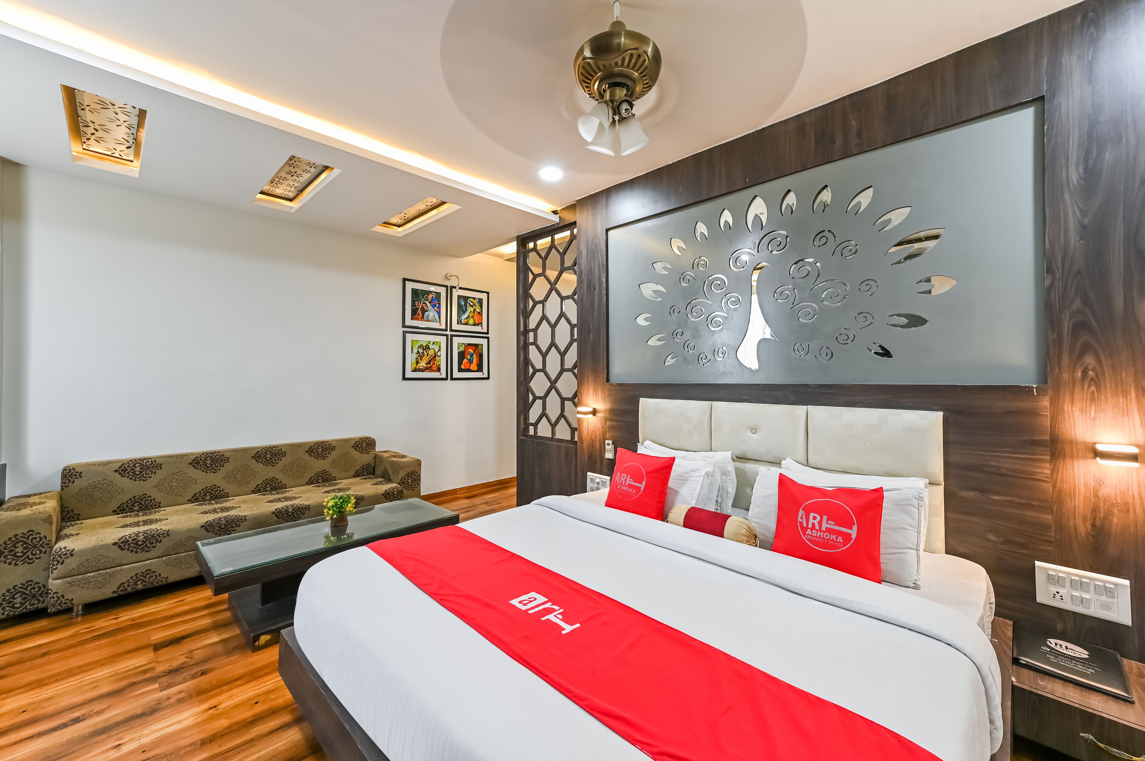 A hotel room with a bed, a sofa, a coffee table, and a decorative wall piece.