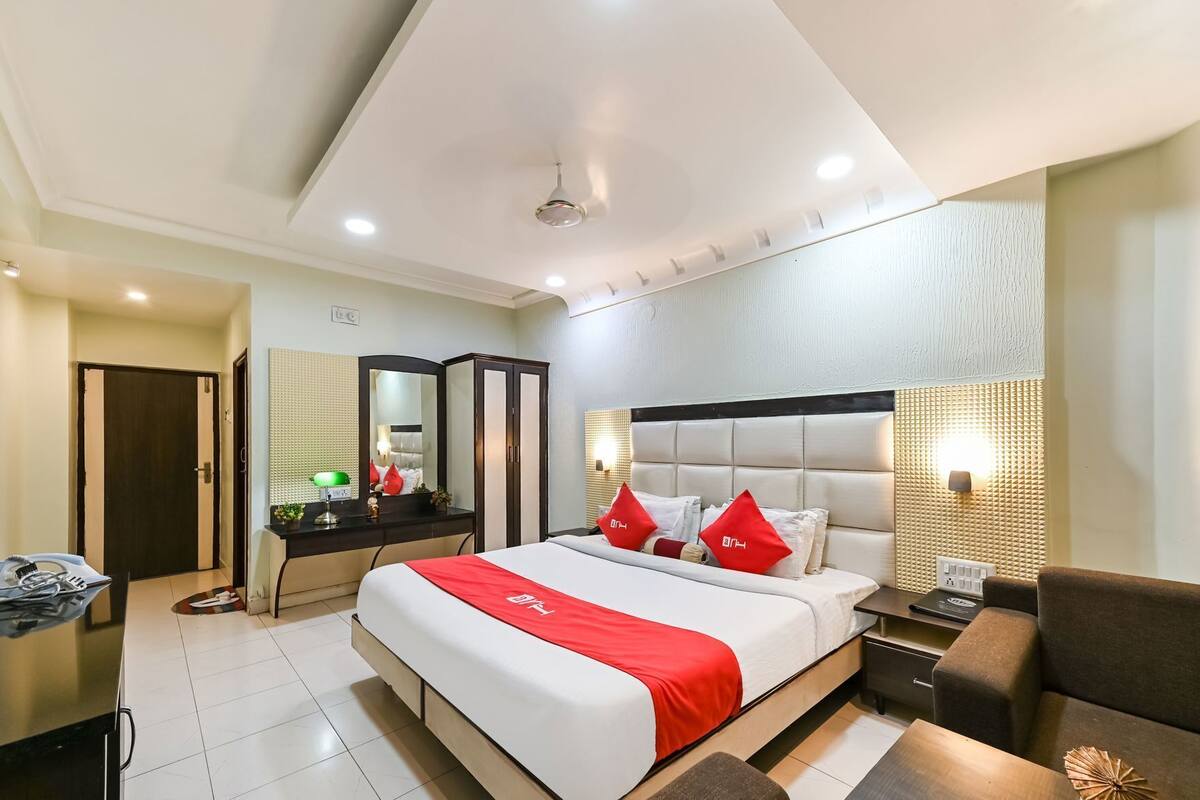 A hotel room with a bed, bedside table, desk, chair, and a mirror.