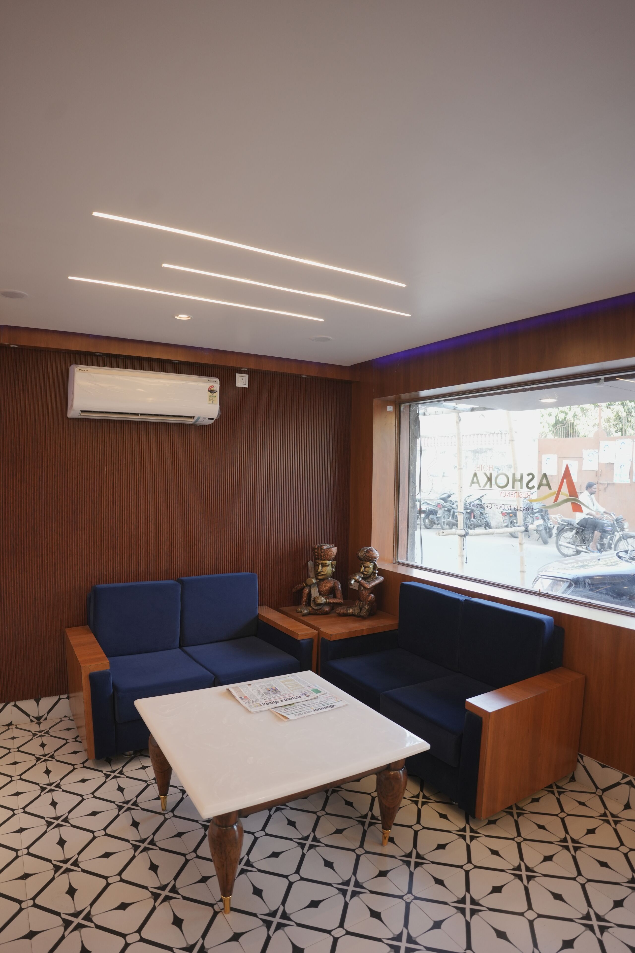 A modern waiting area with a blue sofa, a white table, and patterned floor tiles.