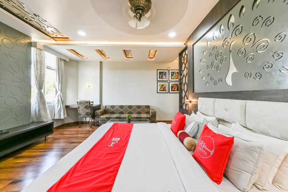 A hotel room with a large bed, a sofa, a desk, and a decorative wall.