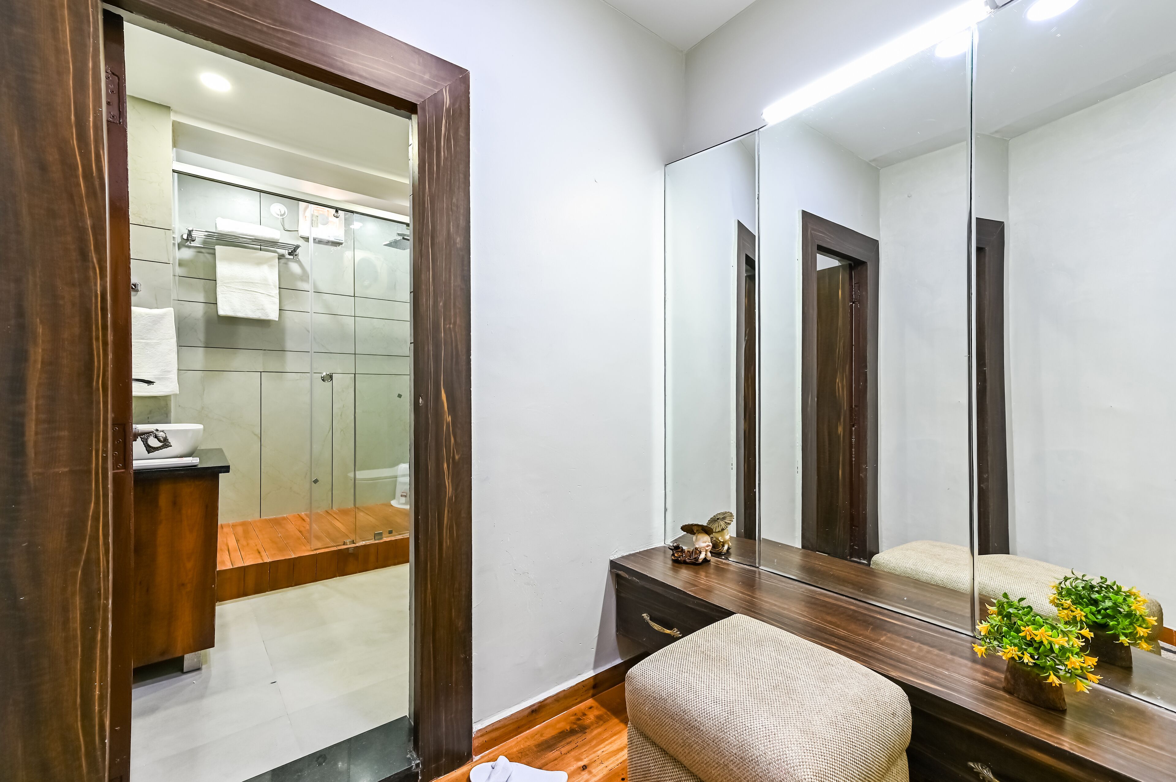 A modern bathroom with a glass shower enclosure, a wooden vanity, and a large mirror.