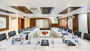 A conference room with a long table, black chairs, water bottles, and nameplates. - Ashoka Residency Hotel (Bhilwara)