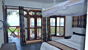 Ein Schlafzimmer mit einem großen Bett, Meerblick und einem Balkon mit Tisch und Stühlen.