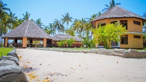 Ein Resort mit strohgedeckten Hütten und einem Sandstrand.