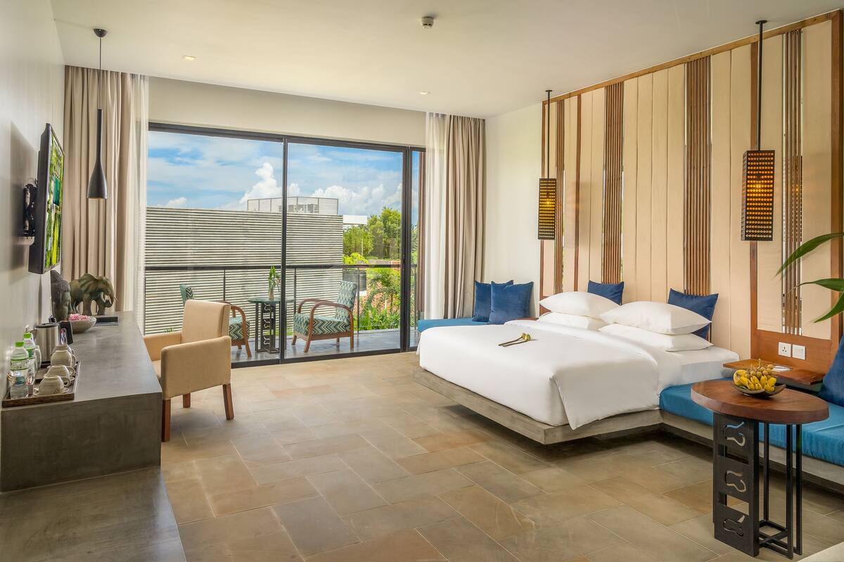 Habitación de hotel moderna con una cama grande, un escritorio y un balcón con vistas.
