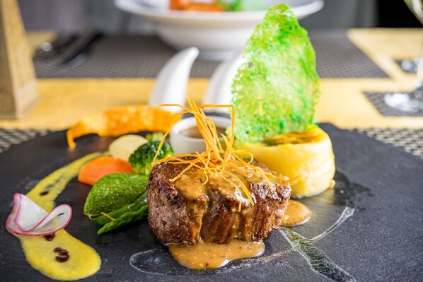 Un plato negro con carne, salsa y vegetales.