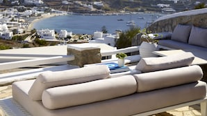 A modern outdoor seating area with a view of a coastal town and the sea. - Kallos of Mykonos (Mykonos)
