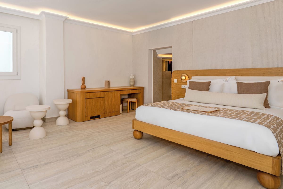 A modern bedroom with a wooden bed, a wooden dresser, a white chair, and a small round table.