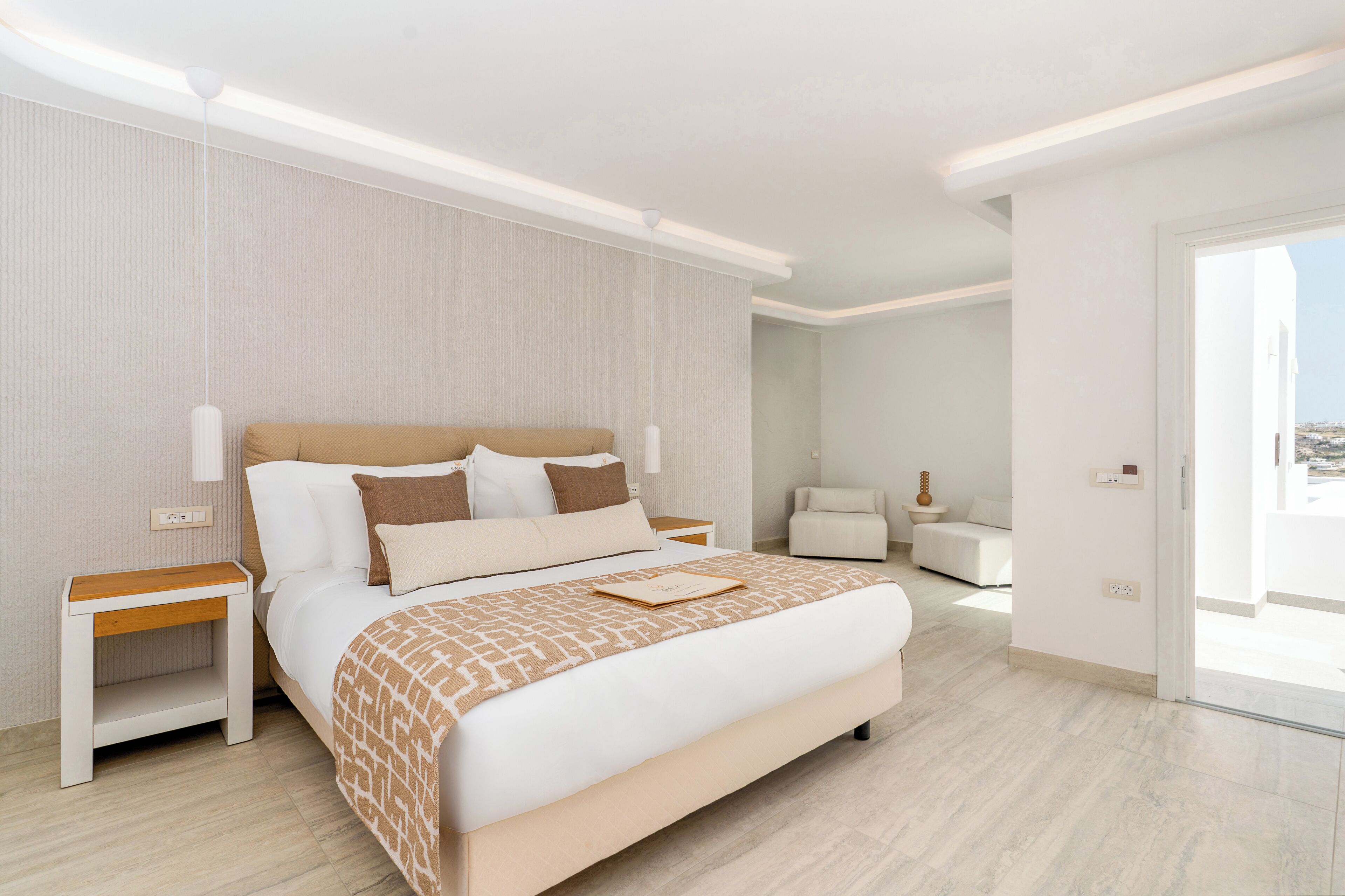 Ein modernes Hotelzimmer mit einem großen Bett, Nachttischen, einer Couch und Blick auf die Stadt.