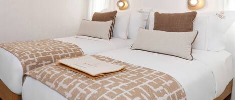 A double bed with a patterned throw, two pillows, a bedside table, and wall-mounted lighting.