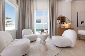 A modern hotel room with a balcony, white furniture, a round coffee table, and a wooden sideboard. - Kallos of Mykonos (Mykonos)