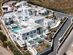 A modern resort with multiple buildings, a swimming pool, and a road.