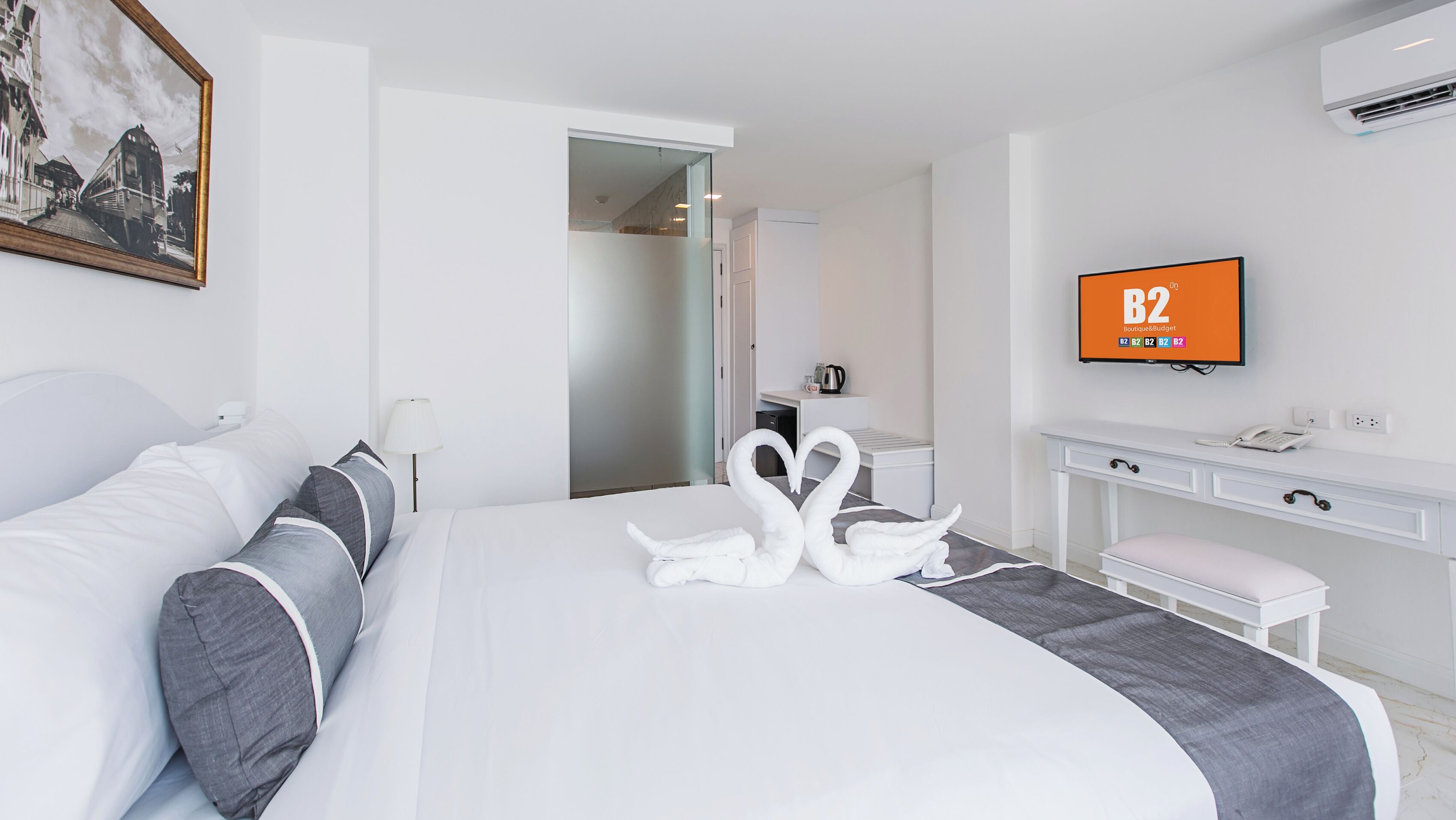 Une chambre d’hôtel avec un grand lit, un bureau, une télévision et une salle de bain visible à travers une porte ouverte.