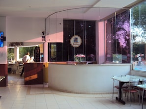 A restaurant with a counter, tables, and chairs. - Apartamento Grand Dolphin - Férias em Caldas Novas (Caldas Novas)