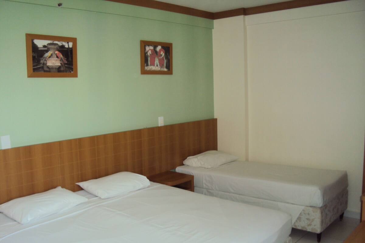 Ein Hotelzimmer mit zwei Einzelbetten, einem Holzkopfschild und zwei gerahmten Bildern an der Wand.