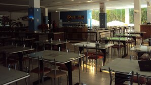 A spacious dining area with multiple tables and chairs, a counter with a display, and large windows providing natural light. - Apartamento Grand Dolphin - Férias em Caldas Novas (Caldas Novas)